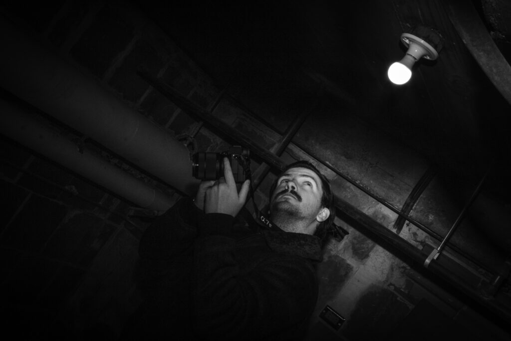 Man holding camera looks up at light bulb.