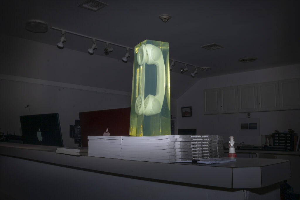 Photography in a dark room, with a telephone in a transparent green cube.