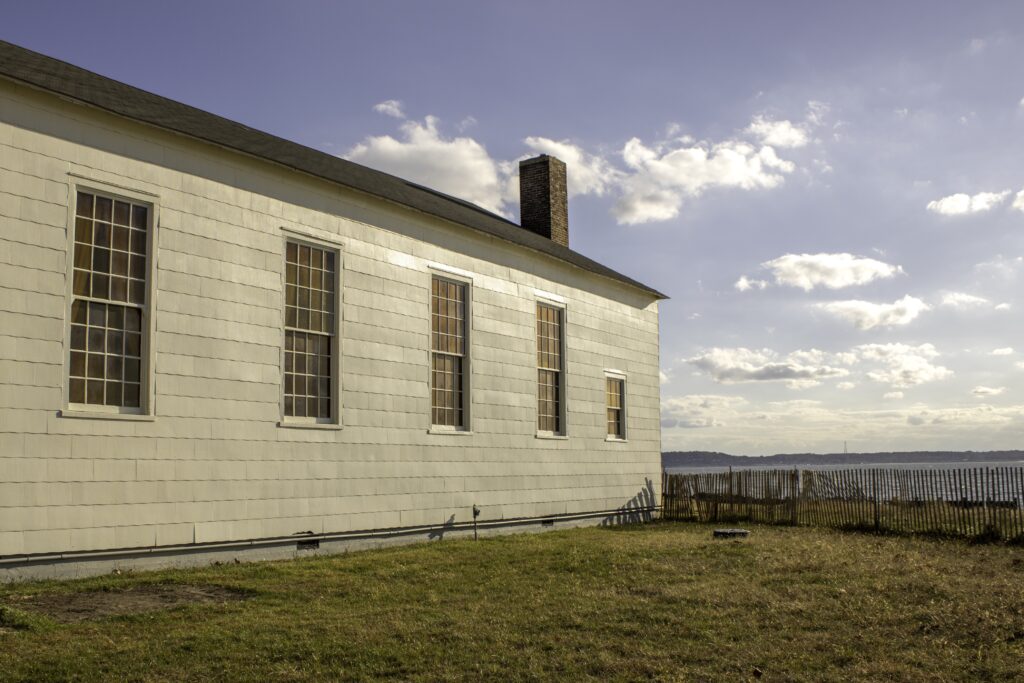 Photography of the side of a building, with a chimney and several windows.